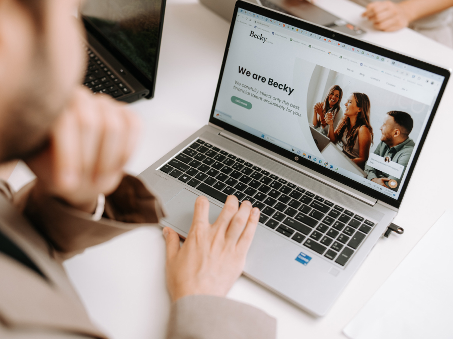 A candidate reviewing a company's website and preparing for an interview, with a laptop showing the company’s page.